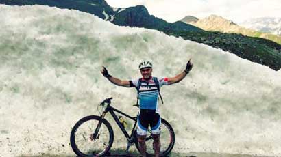 Mountainbiker mit Mountainbike vor Gletscherwand
