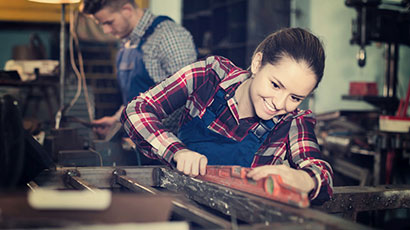 Junge Frau am Arbeiten im Handwerk kariertes Hemd und Arbeitshose