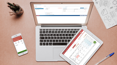 Bild Schreibtisch mit Laptop Tablet Smartphone und Personaleinsatzplanung Screenshot und Stiftebox